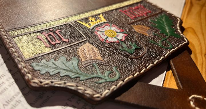 Der mittelalterliche Armschutz aus Leder mit halbfertiger Bemalung – goldene Verzierungen werden gerade aufgetragen