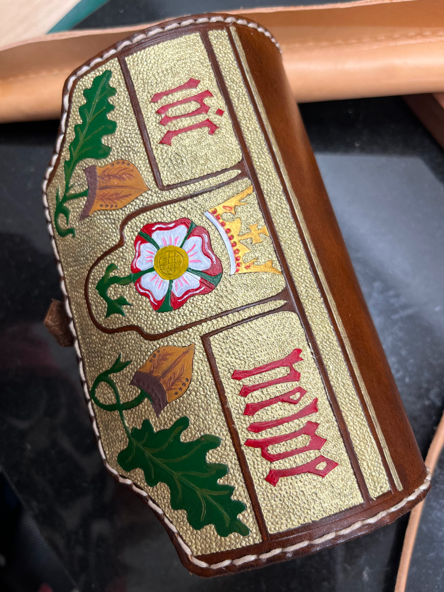 Fertiger, gebogener mittelalterlicher Armschutz aus Leder, punziert, mit goldener Farbe verziert und vernäht – bereit für den Einsatz